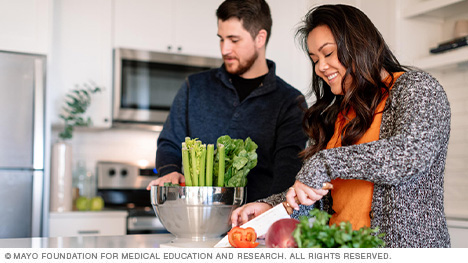 A couple prepares a salad.
