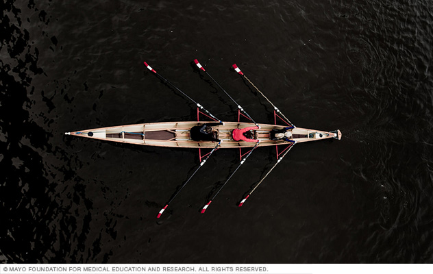 Three rowers pull together on water.